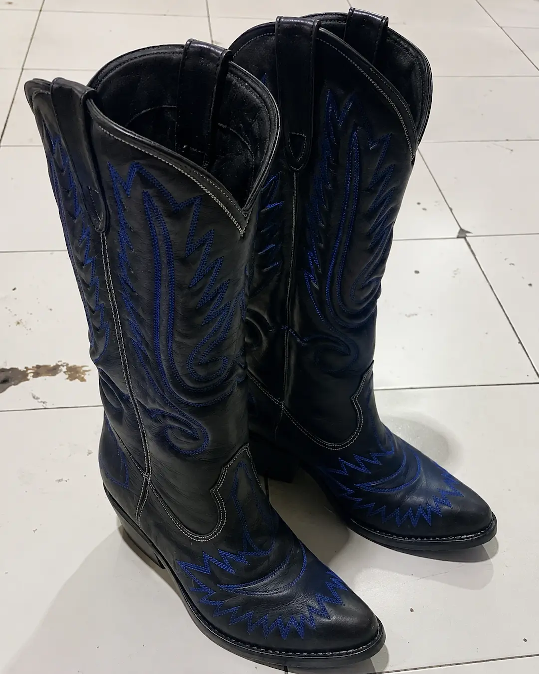 Cowboy boots kulit hitam dengan detail bordir biru tua.